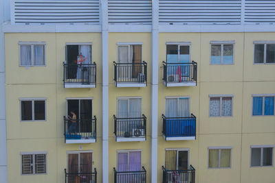 Full frame shot of residential building with shirtless man standing in balcony