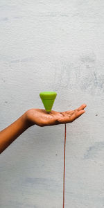 Hand holding drink against wall