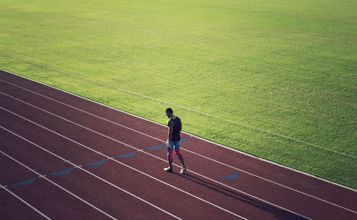 Rear view of man running on green landscape