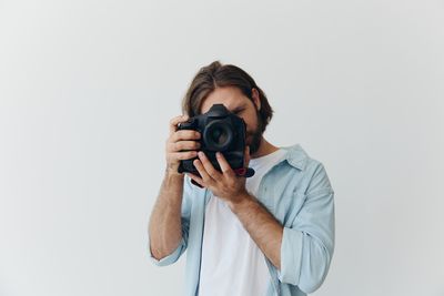 Young woman photographing against white background