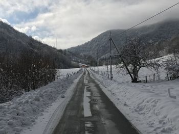 Road amidst snow covered mountain against sky