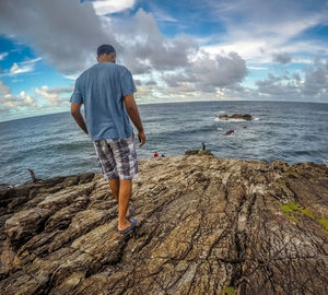 Rear view of man standing on beach against sky