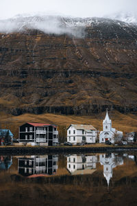 Buildings with water reflection against sky during winter