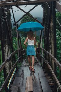 Rear view of woman walking on footbridge