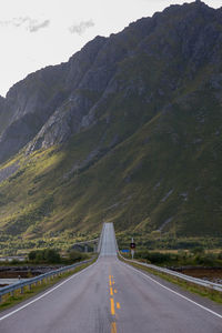 Road leading towards mountains against sky