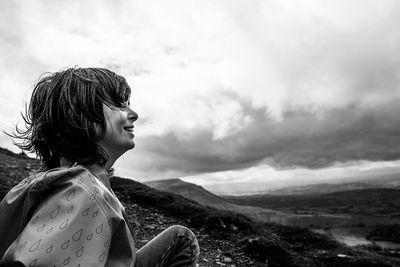 Side view of woman looking against clouds