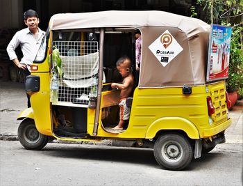 Portrait of woman sitting on yellow car on street