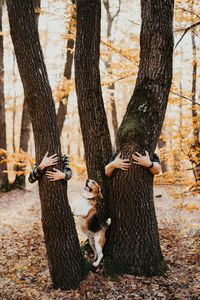 Low section of a couple standing on tree trunk during autumn