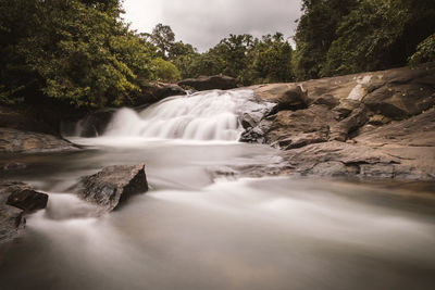 Scenic view of waterfall in forest against sky