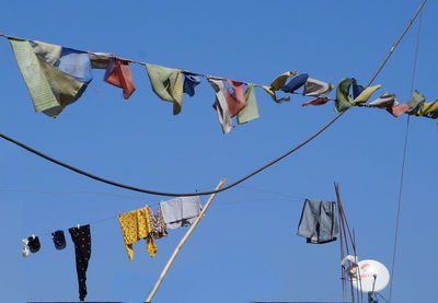 Low angle view of clothes drying against clear blue sky