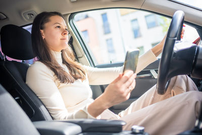 Portrait of young woman sitting in car