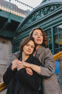 Portrait of lesbian couple embracing on staircase in city