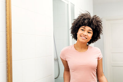 Smiling teenage girl looking in mirror at home