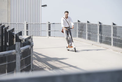 Businessman with backpack riding his e-scooter