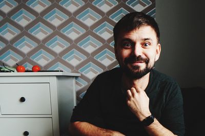 Portrait of man sitting against wall at home