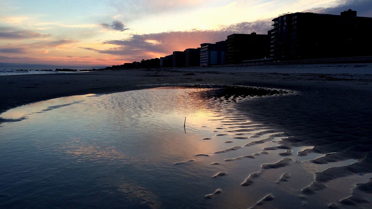 water, sunset, beach, sea, sky, architecture, built structure, building exterior, shore, sand, cloud - sky, reflection, nature, dusk, scenics, city, coastline, tranquil scene, tranquility, outdoors