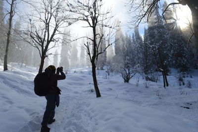 People photographing snow covered trees during winter