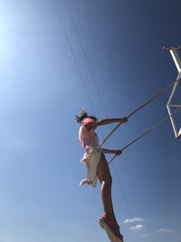 Low angle view of woman holding rope against sky