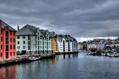 Sailboats moored on canal by buildings against sky