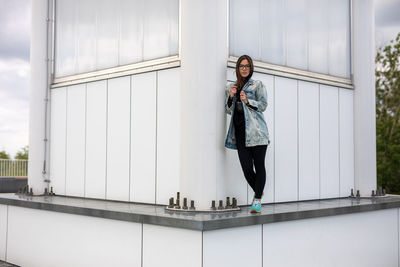 Portrait of young woman standing against railing