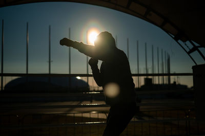 Rear view of woman jumping against sky during sunset