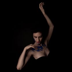 Young woman with body paint against black background