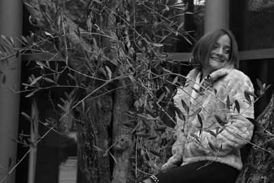 Portrait of smiling young woman against tree