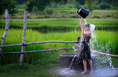 Full length of woman taking bath by well at farm