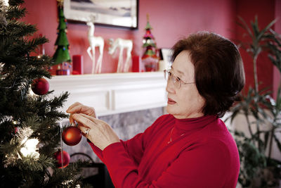 Woman decorating christmas tree at home