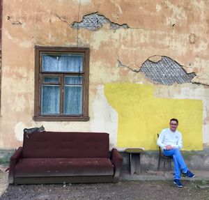 Full length portrait of man against wall of building