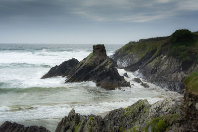 Scenic view of sea by cliff against sky