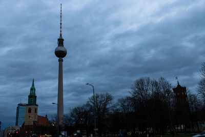 Communications tower in city against sky