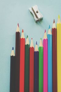 Close-up of colored pencils with sharpener over blue background