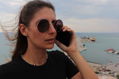 Young woman wearing sunglasses against sea
