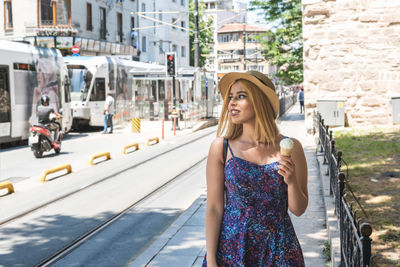 Portrait of young woman standing on road in city