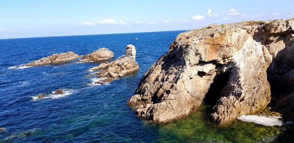 Rock formations by sea against blue sky