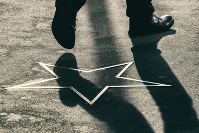 Low section of man walking by star shape marking on road