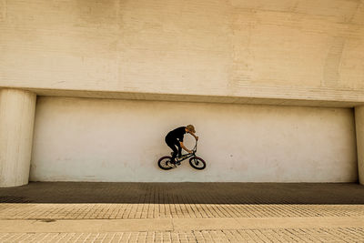 Man performing stunt with bicycle on wall