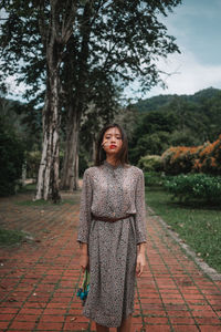 Portrait of smiling young woman standing on footpath