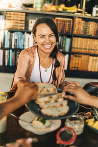 Happy woman giving food to female friends at retreat center