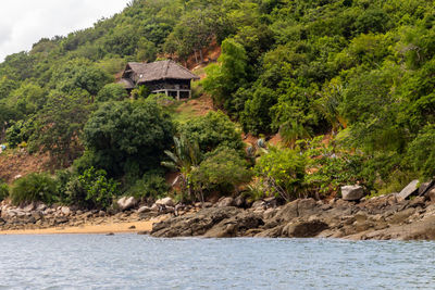 Beach with palm trees and wooden cottage, green mountains at lokobe nature strict reserve
