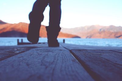 Low section of person standing on pier against sky