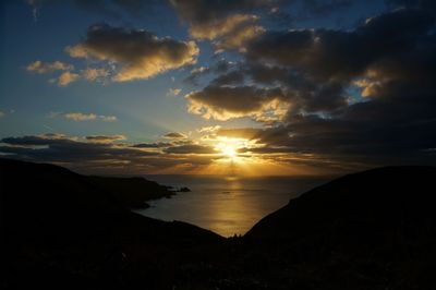 Sun shining through clouds over sea