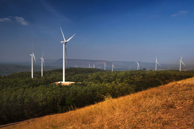 Wind turbines on field against sky