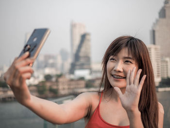 Portrait of young woman using mobile phone in city
