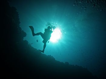 Scuba diver in a giant stride on a wall reef in the caribbean in the sunlight halo