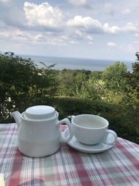Coffee cup on table against sky