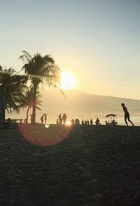 Silhouette people on beach against clear sky