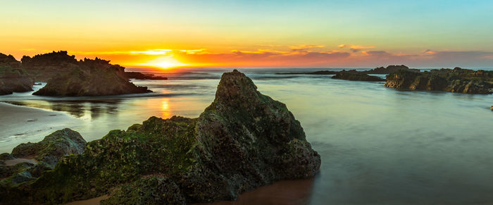 Sunset over rocky coastline with rock formations on the beach