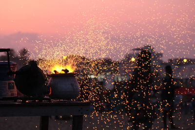 Fire sparks emitting from pot on table during sunset